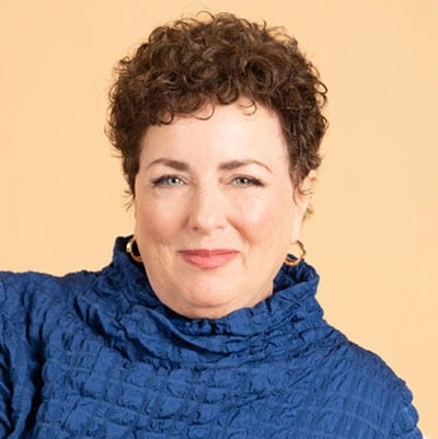 Headshot of Jill Lublin wearing a blue turtleneck