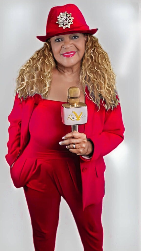 Red-suit-Red-hat-577x1024 picture of raven blair glover holding a microphone and wearing a red suit and hat