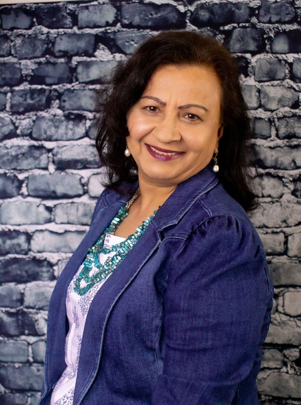 Picture of Ritu Chopra wearing a blue blazer, white shirt, and teal bead necklace