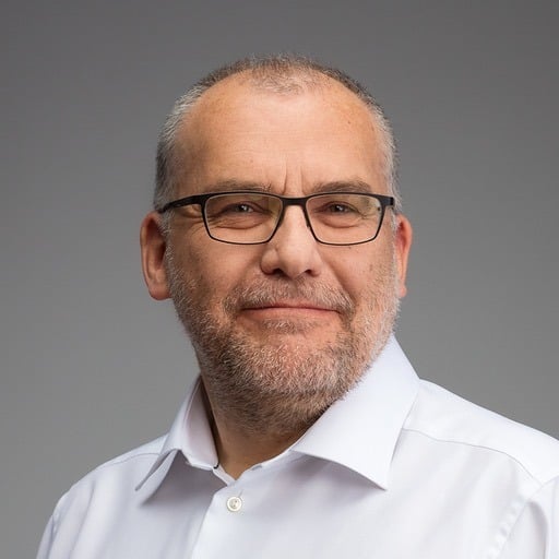 Headshot of Vaclav Vincalek in a white buttoned shirt wearing glasses.